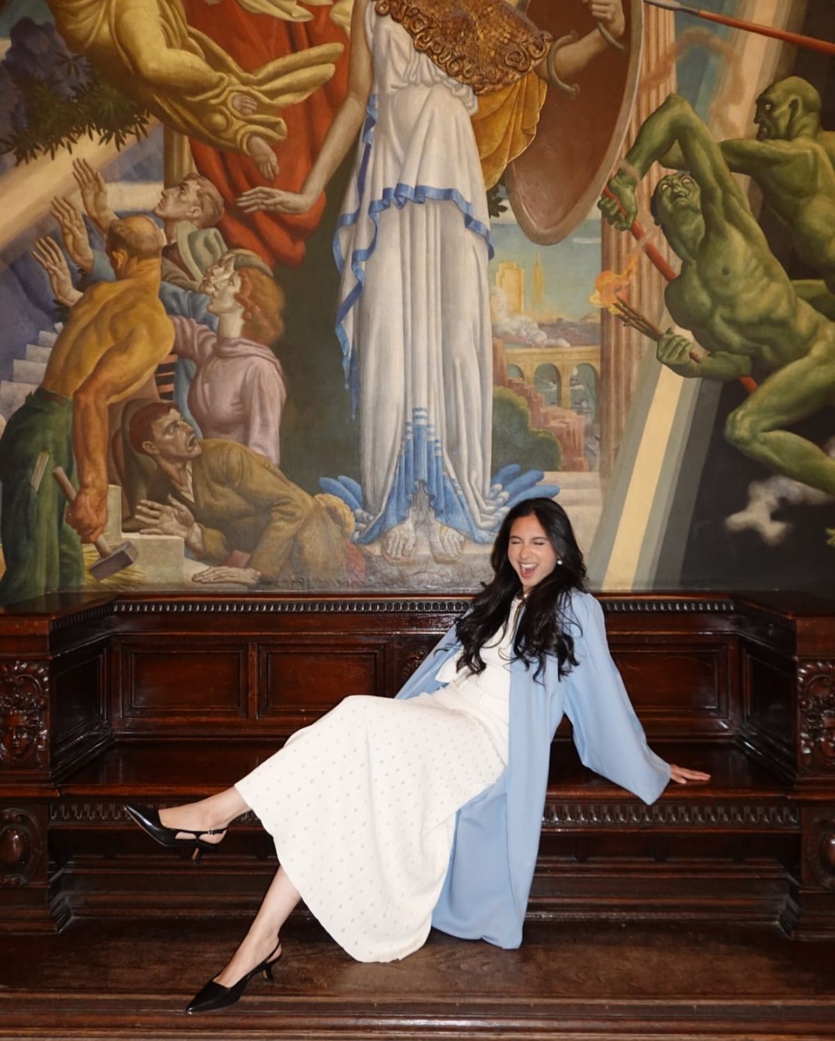 Graduate posing in front of mural